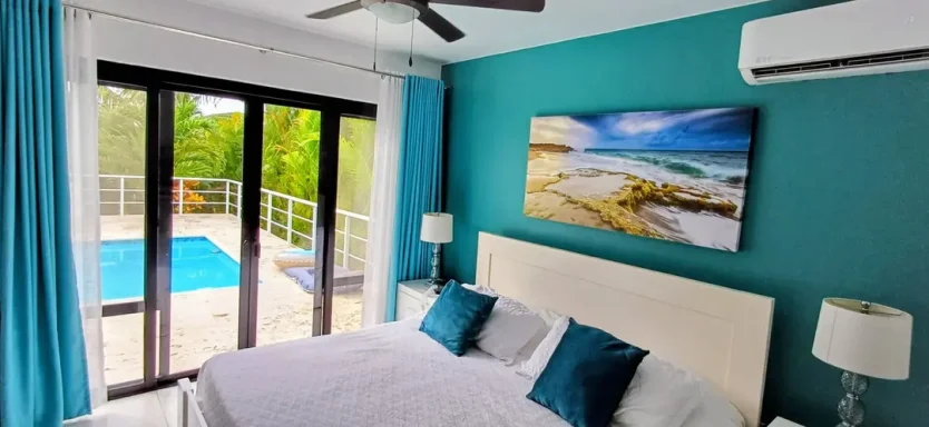 Helles Schlafzimmer mit Poolblick, blau-grüner Wand und schöner Strandmalerei.
