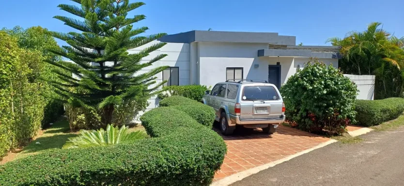 Haus mit Garten, grünen Hecken und einem silbernen Auto auf der Einfahrt.