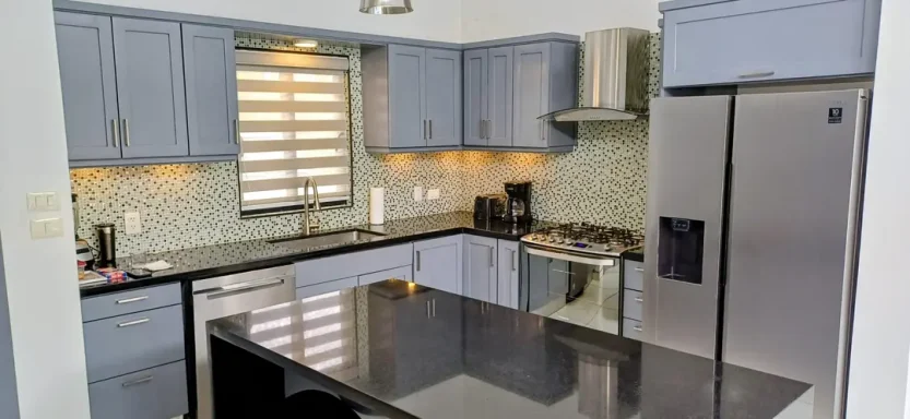 Moderne Küche mit blauen Schränken, schwarzem Granit und Edelstahlgeräten.