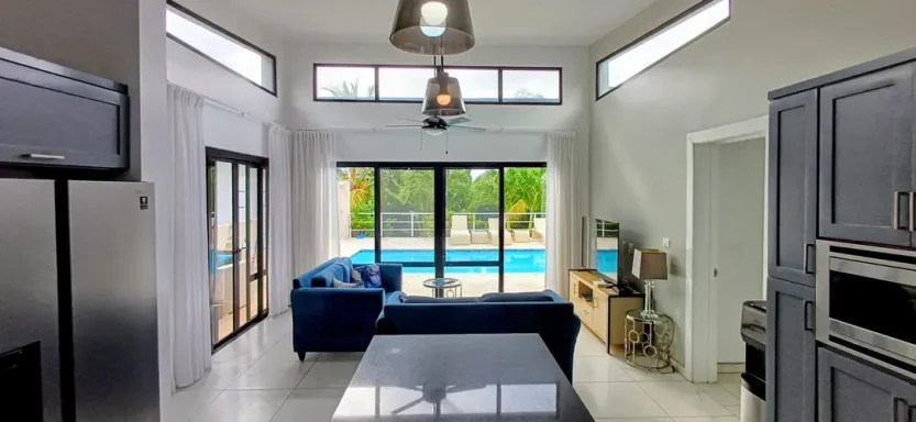 Moderne Küche mit Fenstern, Blick auf den Pool und stilvollem blauen Sofa.