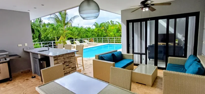 Moderne Terrasse mit Sitzbereich, Pool und Grünanlage im Hintergrund.